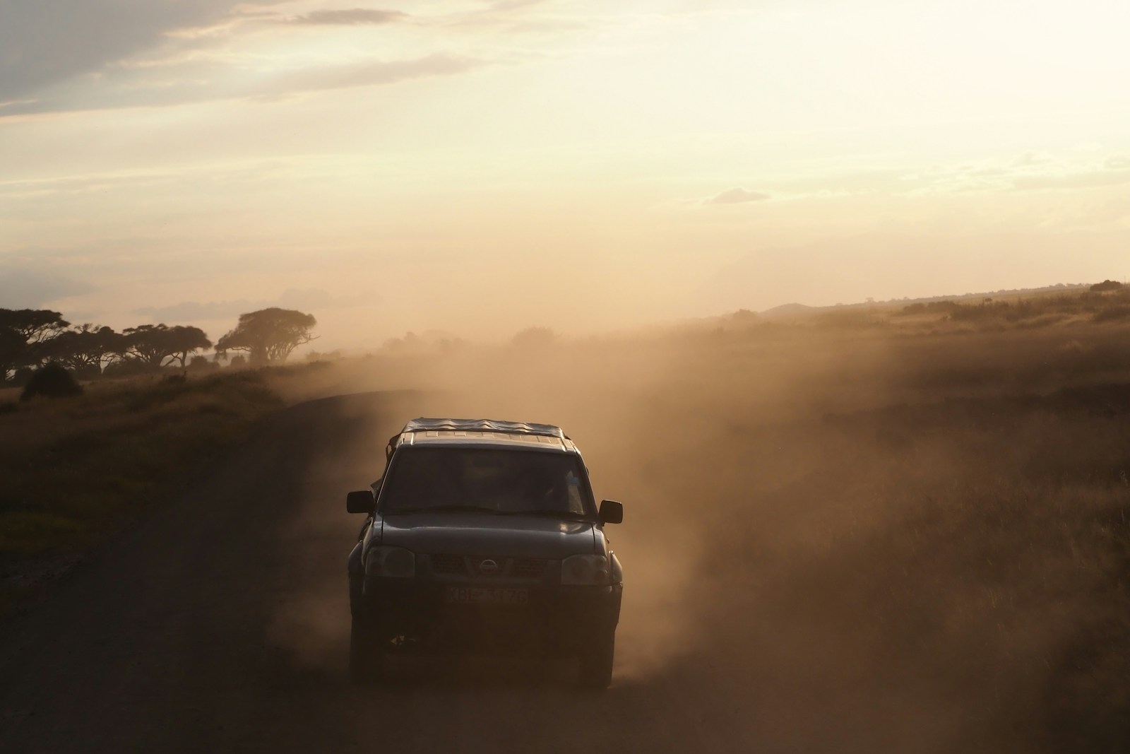 Un coche circulando por un camino de tierra en medio del campo